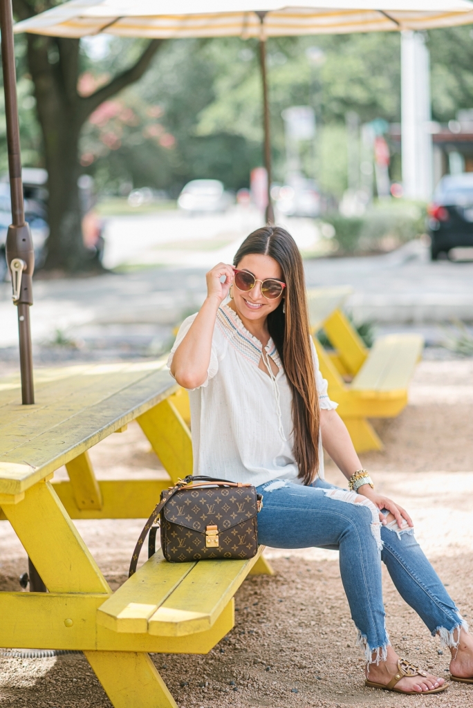 Rainbow smocked top styled for summer by top US fashion blog, LuxMommy: image of a woman wearing a Madewell rainbow smocked top, Express mid rise jeans, Tory Burch flip flops, Kendra Scott drop earrings, Michele diamond watch, Stella & Dot spike bracelet and Louis Vuitton crossbody bag.